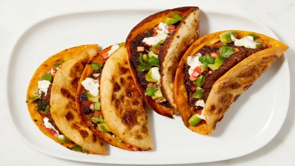 Best Smash Burger Tacos (Healthy Version) served with crispy tortillas, seasoned beef, fresh avocado, tomatoes, herbs and creamy sauce on a white plate.