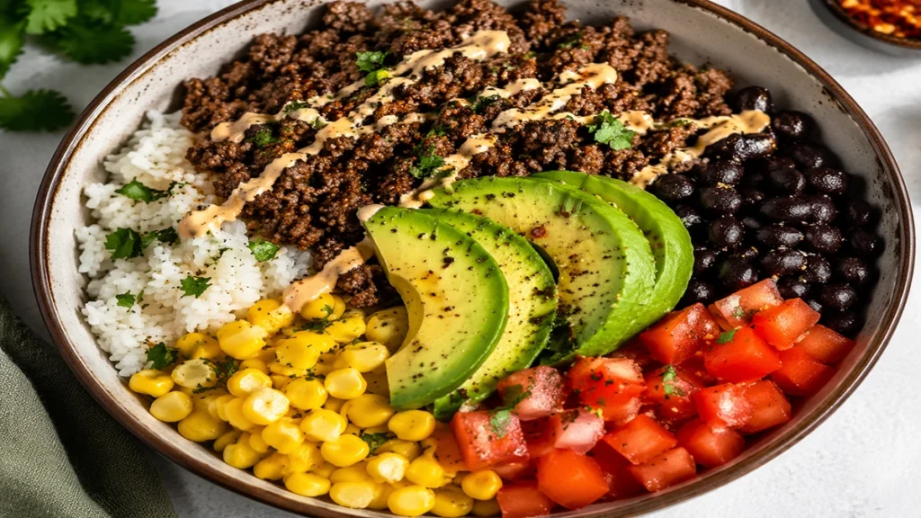 Ground Beef Protein Bowl with rice, avocado, black beans and fresh vegetables healthy high-protein meal.