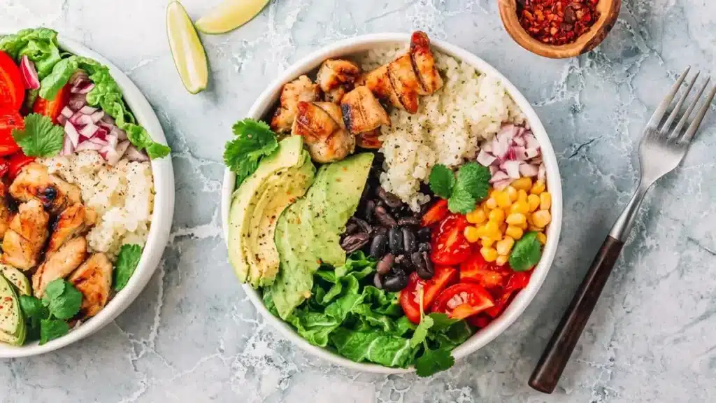 High Protein Chicken Burrito Bowl with grilled chicken avocado rice black beans corn and fresh vegetables.