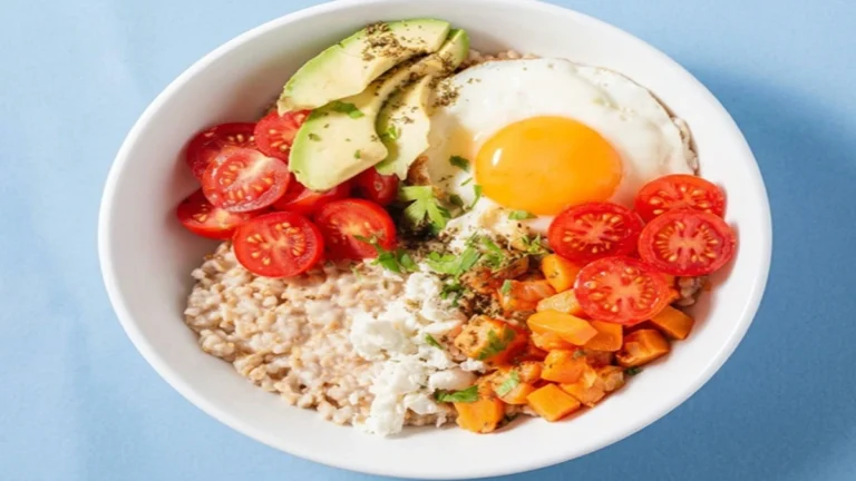 Savory Oatmeal Breakfast Bowl with creamy oats, fried egg, avocado slices, cherry tomatoes, sweet potatoes, and crumbled cheese in a healthy high-protein breakfast bowl.