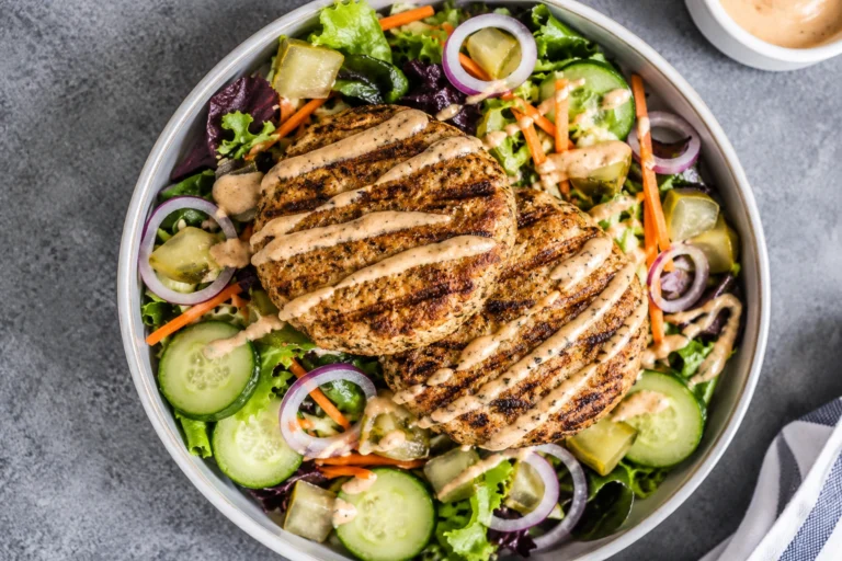 Air Fryer Turkey Burger Bowls topped with juicy turkey patties, fresh lettuce, cucumbers, carrots, red onions, pickles, and creamy burger sauce.