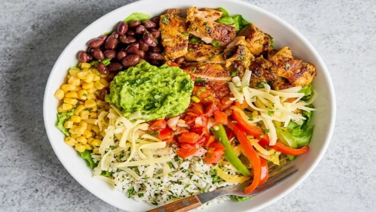 Top view of a colorful Classic Shredded Chicken Burrito Bowl, containing grilled chicken, rice, black beans, corn, guacamole, salsa, and cheese.
