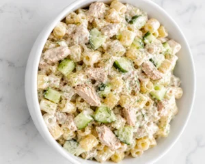 Creamy Crunchy Pasta Tuna Salad served in a white bowl with cucumber chunks and tender tuna pieces.