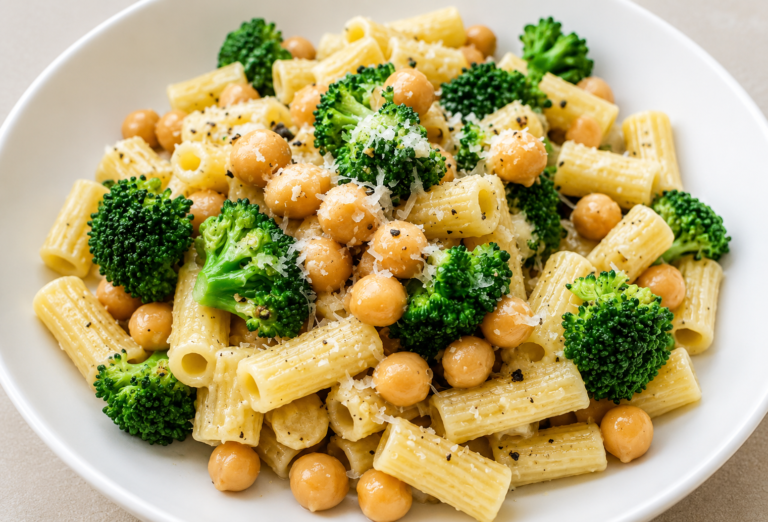Bowl of Garlic Olive Oil Broccoli Chickpea Pasta with rigatoni, broccoli florets, chickpeas, parmesan cheese, and black pepper in a white bowl.