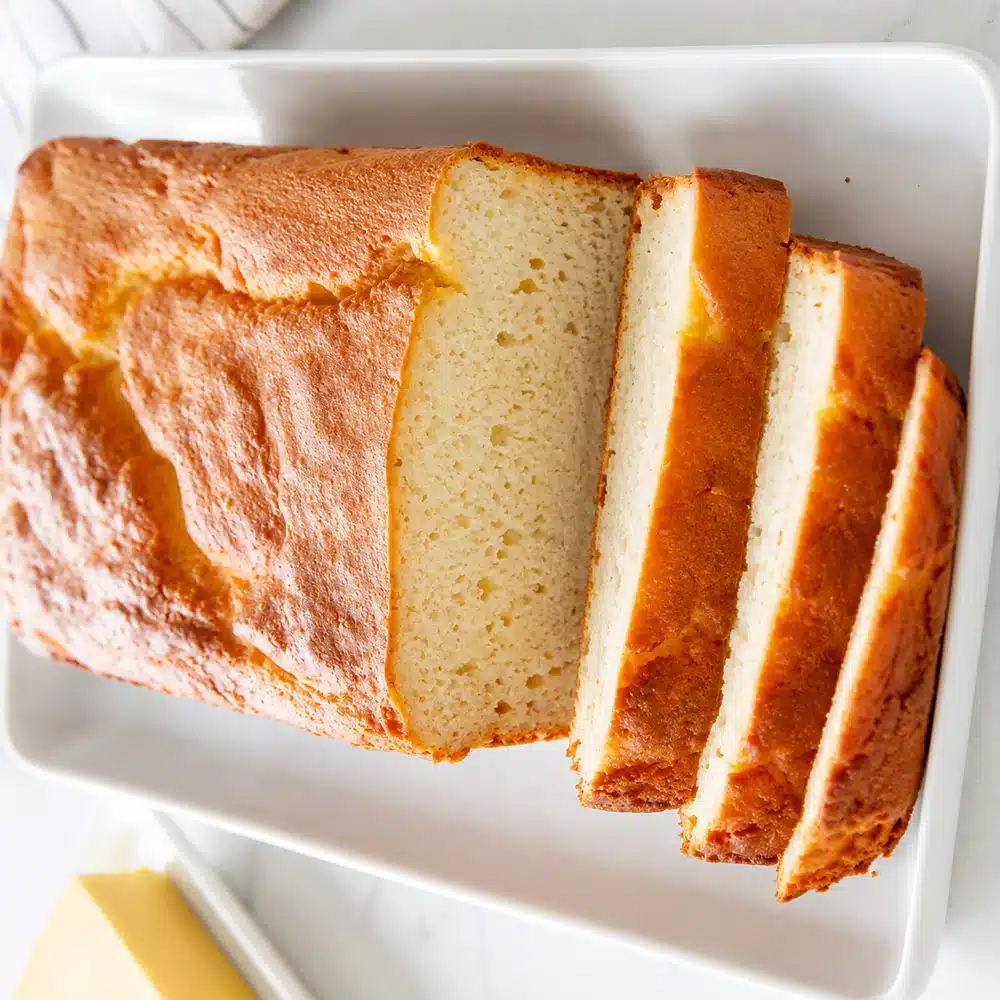 Fresh homemade Keto Bread Without Yeast sliced on a white serving platter with a soft fluffy texture and golden crust.