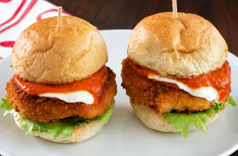 Garlic Parmesan Turkey Burgers served on a white round plate with crispy turkey patties, lettuce, creamy sauce, and rich tomato topping.