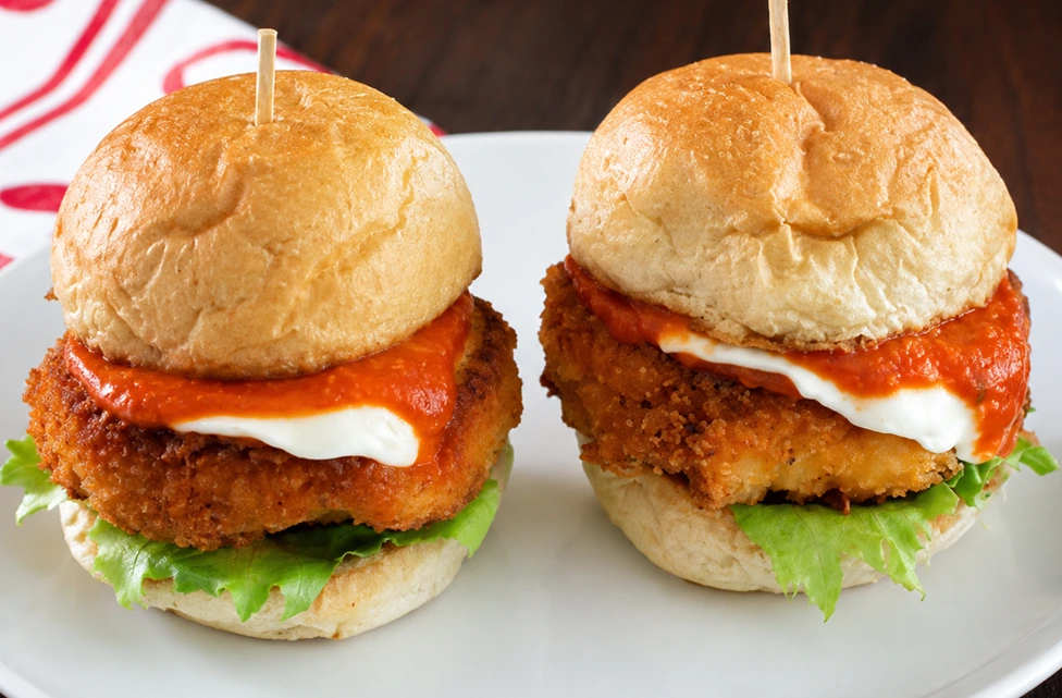 Garlic Parmesan Turkey Burgers served on a white round plate with crispy turkey patties, lettuce, creamy sauce, and rich tomato topping.