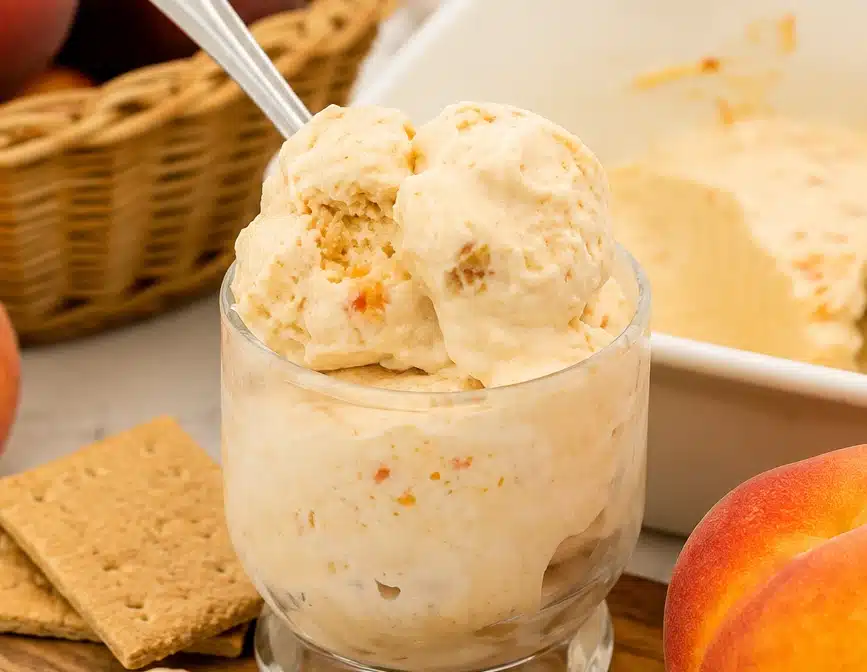 Peach Cottage Cheese Ice Cream served in a glass dessert cup with creamy peach swirls and fresh peaches on the side.