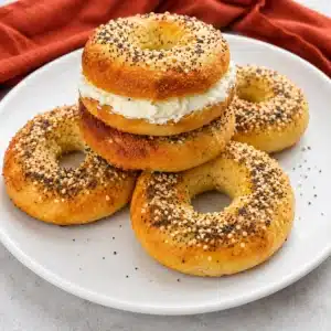 Freshly baked Cottage Cheese Bagels served on a white round plate, topped with everything bagel seasoning and filled with cream cheese. These soft, chewy, high-protein bagels are perfect for a healthy breakfast or meal prep.