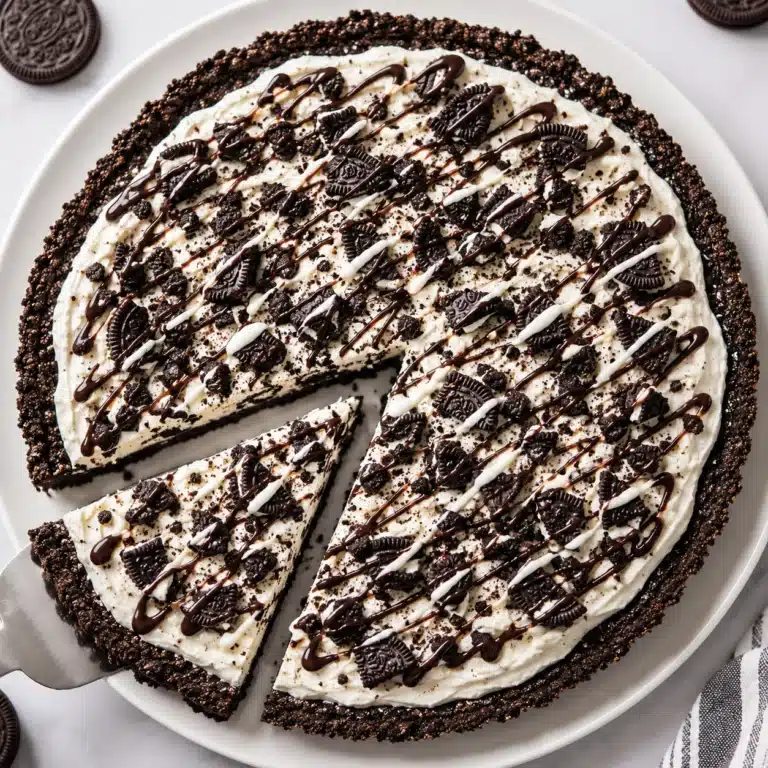 Oreo Dessert Pizza with a crunchy Oreo cookie crust, creamy no-bake filling, crushed Oreo cookies, and chocolate drizzle served on a white plate.