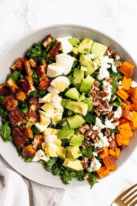 Autumn Cobb Salad with roasted sweet potatoes, avocado, hard-boiled eggs, crispy chicken, feta cheese, pecans, and kale served in a bowl for a healthy fall lunch or dinner.
